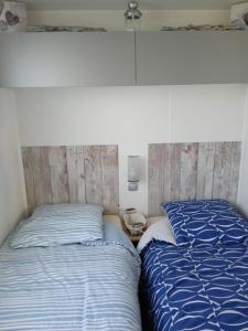 - 2 lits installés l'un à côté de l'autre dans une chambre dans l'établissement Mobil home-Les Lins Bleus, à Biville-sur-Mer
