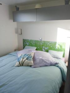 a bed with three pillows on it in a bedroom at Mobil home-Les Lins Bleus in Biville-sur-Mer