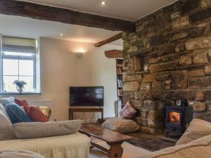 a living room with a stone wall and a fireplace at Sunnyside Barn in Cracoe
