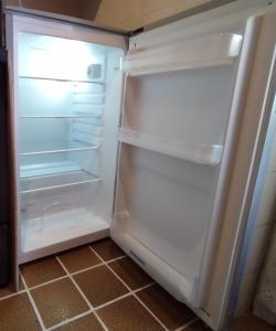 pusta lodówka z otwartymi drzwiami w kuchni w obiekcie GRAYNITE-Meadows Apartment w mieście Ponte di Legno
