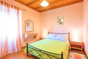 a bedroom with a green bed and a window at Archontiko Aliki in Sgourádes