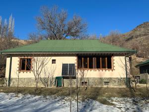 una pequeña casa con techo verde en la nieve en Hayat Guesthouse Nuratau Mountains, en Yukary-Ukhum