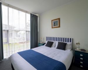 a bedroom with a large bed and a large window at Mermaid Apartments in Merimbula