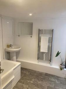 uma casa de banho branca com um lavatório e um espelho em Charming holiday apartment in central Woodbridge em Woodbridge