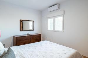 Habitación blanca con cama y espejo en Estancia Lucía en La Orotava