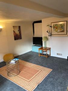 a living room with a table and a television at Charming holiday apartment in central Woodbridge in Woodbridge