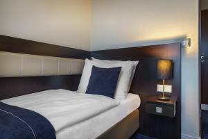 a hotel room with a bed with a blue accent wall at Novum Hotel Continental Hamburg Hauptbahnhof in Hamburg