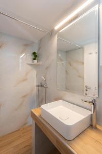 KALYPSO ACCOMMODATION SIFNOS في فاثي: حمام مع حوض أبيض ومرآة