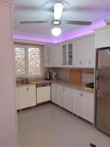 a kitchen with white cabinets and a ceiling fan at Alanya Bektaslar 3+1 lüks daire in Alanya