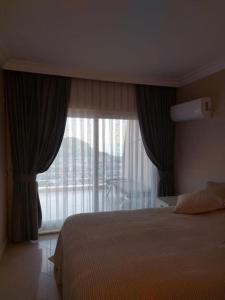 a bedroom with a bed and a large window at Alanya Bektaslar 3+1 lüks daire in Alanya