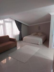 a bedroom with a bed and a couch and a window at Alanya Bektaslar 3+1 lüks daire in Alanya