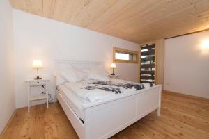 - une chambre avec un lit blanc et un plafond en bois dans l'établissement La Grobla - Die ruhige & heimelige Ferienwohnung, à Zillis