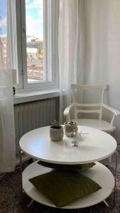 une table et une chaise blanches dans une chambre avec fenêtre dans l'établissement Viehättävä asunto Heinolan keskustassa, à Heinola