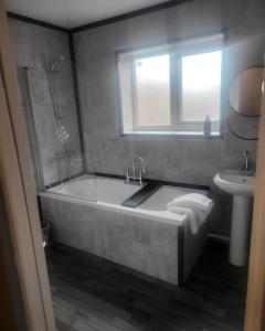 La salle de bains est pourvue d'une baignoire, d'un lavabo et d'une fenêtre. dans l'établissement Dundas Apartments - Furnished Short Lets, à Sunderland