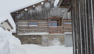 una casa en la nieve con nieve cayendo sobre ella en La Grobla - Die ruhige & heimelige Ferienwohnung, en Zillis