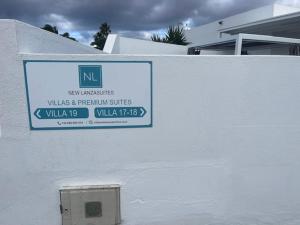 a sign on the side of a white wall at VILLAS NEW LANZASUITES PLUS in Playa Blanca