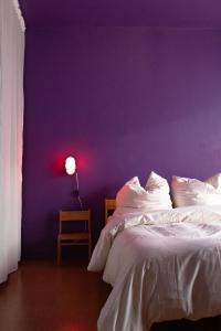 una camera da letto con una parete viola, un letto e una lampada di new design apartment a Duisburg