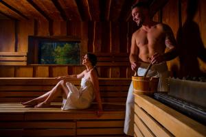 Ein Mann und eine Frau sitzen in einer Sauna in der Unterkunft Hotel Grand Jasná in Demänovská Dolina