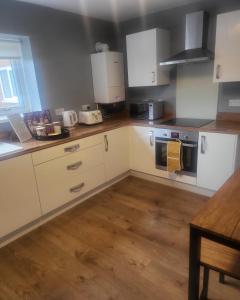 uma cozinha com armários brancos e piso em madeira em Dundas Apartments - Furnished Short Lets em Sunderland