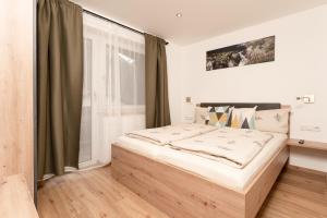 1 dormitorio con 1 cama grande y ventana en Bergnest Oetztal - Appartements, en Umhausen