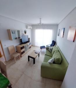 een woonkamer met een groene bank en een tv bij Green Beach -2 Dormitorios in Oropesa del Mar