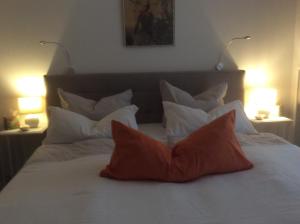 a bed with two orange pillows on it with two lamps at Auszeit am Haffufer in Wilhelmshof