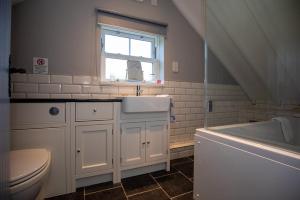 uma casa de banho com um lavatório, um WC e uma janela. em Host & Stay - Millfield Cottage em Chop Gate