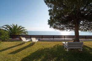a park with two chairs and a table and a tree at Villa Cortesia Maritima - seaside & private in Amarynthos