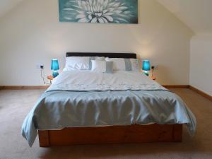 um quarto com uma cama grande com lençóis brancos e almofadas em Barnex em Clippesby