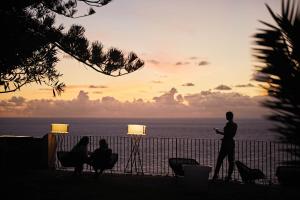 een man die bij zonsondergang langs de oceaan loopt bij Reid's Palace, A Belmond Hotel, Madeira in Funchal