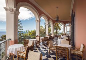 a restaurant with tables and chairs on a balcony at Reid's Palace, A Belmond Hotel, Madeira in Funchal