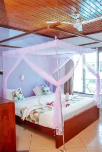 1 dormitorio con 1 cama con dosel en Papillon Garden Bar Villas, en Bamburi
