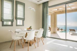 a dining room with a table and white chairs at Villa Sorian Kokkino in Vlachata