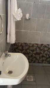 La salle de bains est pourvue d'un lavabo blanc et de serviettes. dans l'établissement THE PLANTAINS PLACE, à Karatina