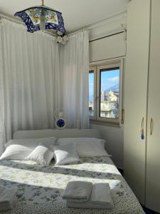 a bedroom with a white bed with a window at Casa Blu Cobalto in Maiori