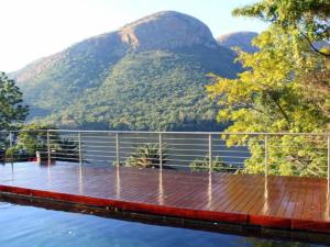 a bridge over the water with mountains in the background at Hartbeespoort Lifestyle Guest House in Hartbeespoort