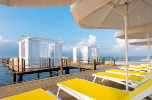 eine Terrasse mit Stühlen und Sonnenschirmen am Meer in der Unterkunft Mary Hotels Alanya in Alanya