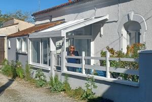 een vrouw die uit een raam van een huis kijkt bij Agréable maison de pêcheur, proche île d'Oléron in Bourcefranc