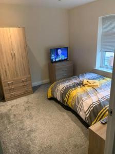 a bedroom with a bed and a flat screen tv at A Lovely Double Bedroom + Private Bathroom in Kettering