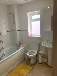 a bathroom with a toilet and a tub and a sink at A Lovely Double Bedroom + Private Bathroom in Kettering