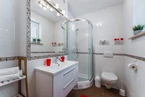 a white bathroom with a shower and a sink at Domki Pod Jarmutą in Szczawnica