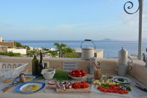 a table with tomatoes and other food items on a balcony at Mariangelica in Ginostra