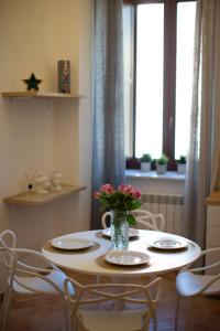 una mesa con sillas y un jarrón de flores. en Dimora del Sole - Intero Appartamento en LʼAquila
