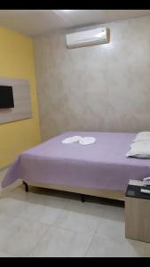 a bedroom with a bed with purple sheets and a light at WJ Hotel in Afogados da Ingàzeira