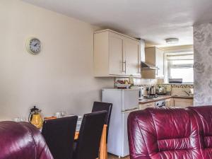 a kitchen with a table and chairs and a white refrigerator at Kite Cottage in Llandeilo