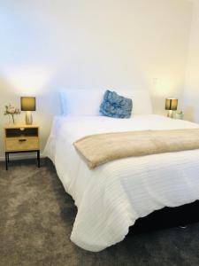 a bedroom with a white bed with a blue pillow on it at Arena,Railway Station Townhouse with Free car park in Christchurch
