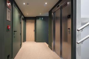 un couloir d'ascenseurs dans un bâtiment aux murs verts dans l'établissement NIREA HOTEL, à Vitoria-Gasteiz