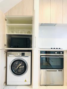 a kitchen with a washing machine and a microwave at Arena,Railway Station Townhouse with Free car park in Christchurch