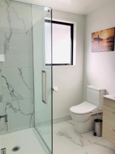 a bathroom with a toilet and a glass shower at Arena,Railway Station Townhouse with Free car park in Christchurch +7 photos