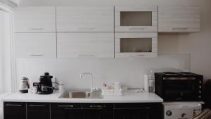 a kitchen with white cabinets and a sink and a microwave at Apartman Barbi in Kupres